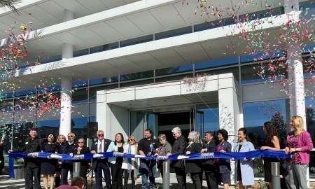 Ribbon cutting with several people and a cloud of confetti